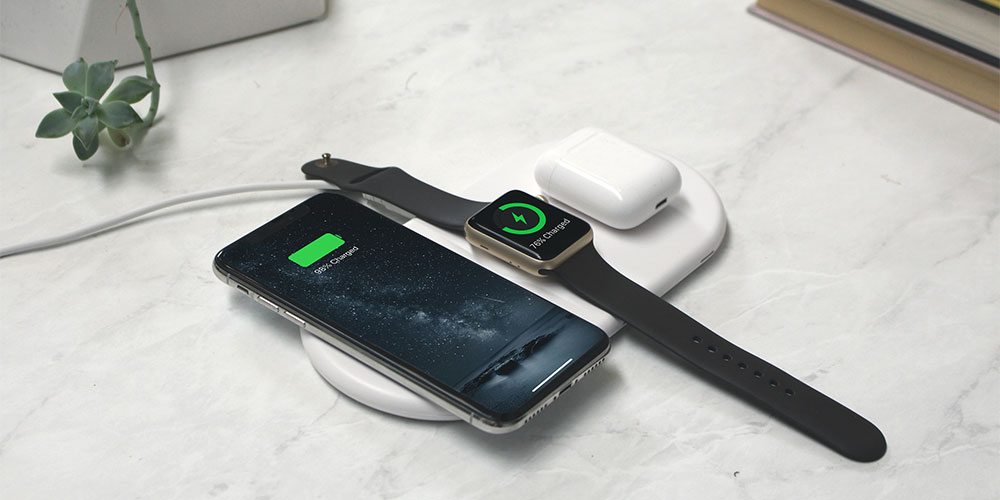 A charging pad with a phone, smart watch, and AirPods case on it