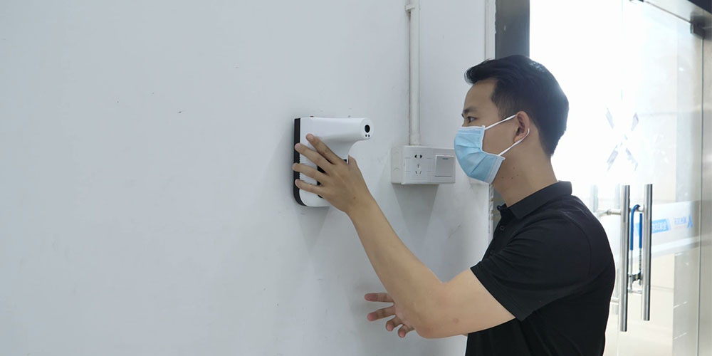 A person using a wall-mounted thermometer 